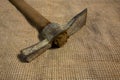 Miner hammer like pickaxe or mattock on bagging fabric background. Closeup view of rustic old hand tool for hard working to