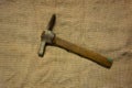 Miner hammer like pickaxe or mattock on bagging fabric background. Closeup view of rustic old hand tool for hard working to