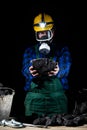 A miner in a helmet with a glowing flashlight and a dust mask on holds a large lump of coal in his hands Royalty Free Stock Photo