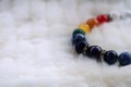 Mineral Chakra color luck fortune stone bracelet on white wool background.