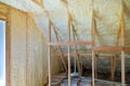 Mineral glass wool in a wooden frame on a inclined wall near the wooden ceiling in a private house