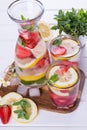 Mineral infused water with strawberry, ice, herb and mint leaves on white background, homemade detox soda