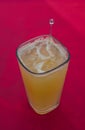 Mineral orangeade in a cubic glass, on a red background