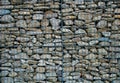 Stone wall of grindstone of light and gray color enclosed behind a metal grid. Royalty Free Stock Photo