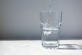 Mineral water pouring into glass on white stone table Royalty Free Stock Photo