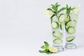 Mineral water with slices cucumber, ice, lime, mint on white wood table with copy space.