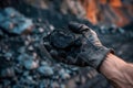 miners hand holding coal with mine backdrop