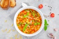 Minestrone soup of fresh vegetables and pasta in a bowl on a gray concrete background. Vegan dish. Copy space Royalty Free Stock Photo