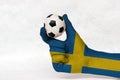 Mini ball of football in Sweden flag painted hand, hold it with two finger on white background. Royalty Free Stock Photo