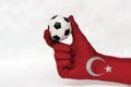 Mini ball of football in Turkey flag painted hand, hold it with two finger on white background. Royalty Free Stock Photo