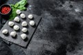 Mini balls of mozzarella cheese, ingredients for salad Caprese. black background. Top view. Copy space