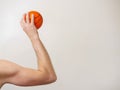 Mini basketball in a muscular hand ready to throw, Copy space, light background