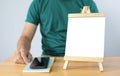 A mini blank whiteboard on wooden table with man and Smartphone