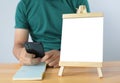 A mini blank whiteboard on wooden table with man and Smartphone