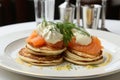 Mini blini pancakes with creamy soft cheese, cold smoked salmon, and fresh dill topping
