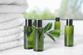 Mini bottles with cosmetic products and towels on wooden window sill