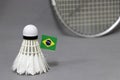 Mini Brazil flag stick on the white shuttlecock on the grey background and out focus badminton racket