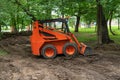 Mini bulldozer or skid steer loader working with earth in public park and performing landscaping works Royalty Free Stock Photo