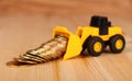 Mini bulldozer truck loading stack coin with pile of gold coin. Royalty Free Stock Photo