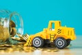 Mini bulldozer truck loading stack coin with pile of gold coin t Royalty Free Stock Photo