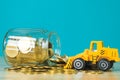 Mini bulldozer truck loading stack coin with pile of gold coin t Royalty Free Stock Photo