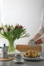 Mini bundt cakes with fruits on plate, two cups of coffee and banch tulip flowers in a vase. Girl holding cup of coffee. Royalty Free Stock Photo