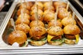 Mini burgers with sesame seeds on a metal tray