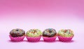 Mini cakes with icing and colorful sprinkles on pink background Royalty Free Stock Photo