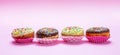 Mini cakes with icing and colorful sprinkles on pink background Royalty Free Stock Photo