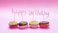 Mini cakes with icing and colorful sprinkles on pink background, text happy birthday decoration Royalty Free Stock Photo