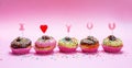 Mini cakes with icing and colorful sprinkles on pink background, text I love you Royalty Free Stock Photo