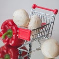 Mini cart shopping witch organic fresh vegetables and mushrooms on light background. Concept of healthy food shopping Royalty Free Stock Photo