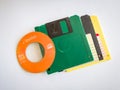 Mini CDs stacked on floppy disks, objects isolated on a white background, the evolution of technology