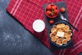 Mini cereal pancakes in blue bowl with buttering toast, strawberries, spoon, glass of milk on grey background, rural Breakfast on