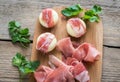 Mini cheese and prosciutto wraps on the wooden board