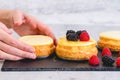 Mini cheesecakes close-up on the kitchen table, woman hands. Decorating cheesecakes with fresh berries Royalty Free Stock Photo