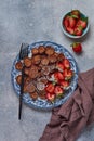 Mini chocolate pancake cereal with strawberries for breakfast on gray concrete table. Trendy home breakfast with tiny pancakes. Royalty Free Stock Photo