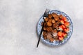 Mini chocolate pancake cereal with strawberries for breakfast on gray concrete table. Trendy home breakfast with tiny pancakes. Royalty Free Stock Photo