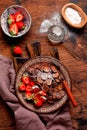 Mini chocolate pancake cereal with strawberries for breakfast on old wooden table. Trendy home breakfast with tiny pancakes. Top Royalty Free Stock Photo