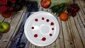 Mini colorful pancakes placed arround a white plate on a wooden background surrounded by fruits