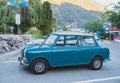 Mini Cooper car parked by the road side. Blue vintage mini car side view. Classic mini cooper