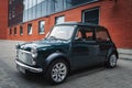 Mini Cooper car is staying parked near red brick wall. Royalty Free Stock Photo