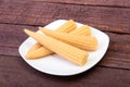 Mini Corn cob preserved on plate on wooden board. Royalty Free Stock Photo