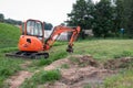A mini crawler excavator is dripping a trench for laying communications.
