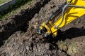 Mini digger digging a hole in the garden along the fence to the drainage pipes.