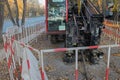 Mini drill machine with a red crawler cab with black equipment, fenced with a protective fence on the street sidewalk of the city