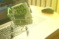 Mini dummy shopping cart on laptop with paper euro banknotes as a concept for online shopping, saving, business and making money a
