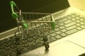 A mini dummy shopping trolley on a lapptop keyboard as a concept for online shopping, saving, business and making money