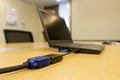 Mini-DVI from laptop to VGA video cable projector on wooden table in meeting room