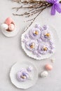 Mini Easter meringue nests with candy eggs on white plate on light background. Festive dessert. Confectionery, bakery, recipe